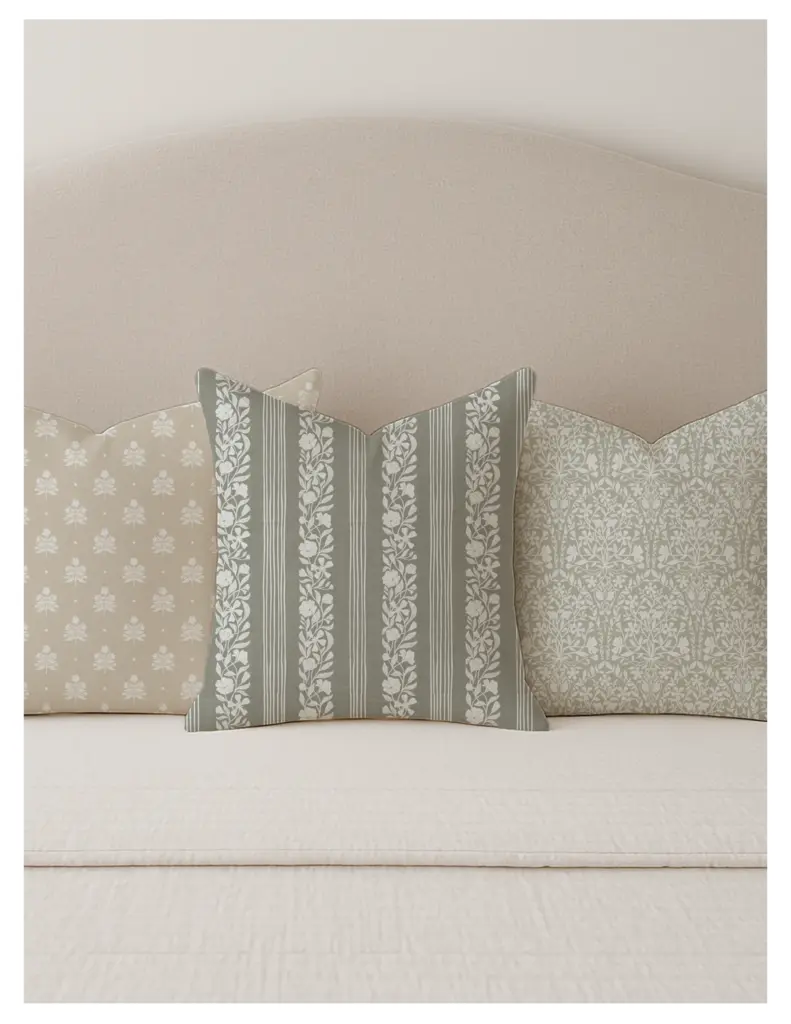 Three decorative pillows arranged on a bed, featuring modern-vintage floral patterns in a light color palette. The designs include a striped pattern with floral motifs, a textured background, and a soft, cozy aesthetic.