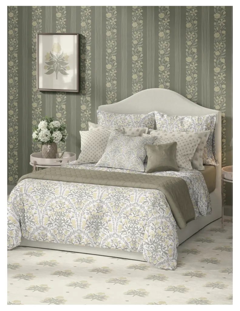 Cozy bedroom décor featuring a floral-patterned bedspread, coordinating pillows, and a botanical print artwork on the wall, all set against a muted green striped wallpaper.