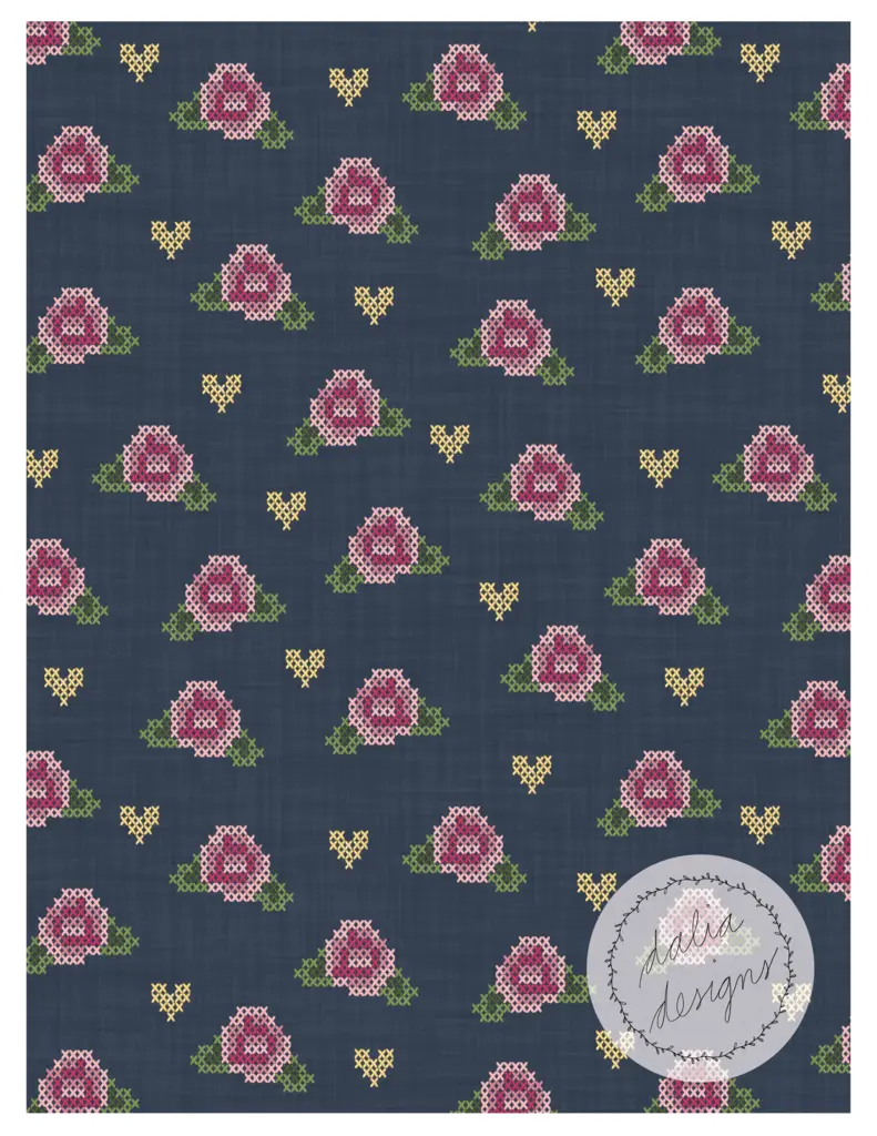 A cross-stitch pattern featuring pink roses and yellow hearts on a dark denim blue background, with a circular logo in the bottom right corner.