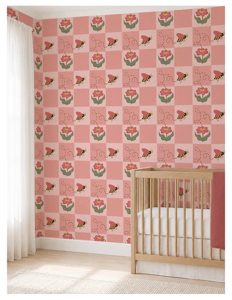 A nursery room featuring a pink and floral patterned wallpaper with bees, alongside a wooden crib.