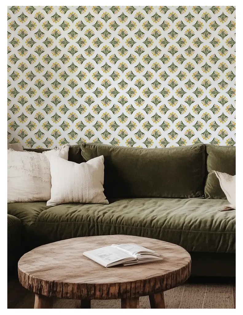 Cozy living room featuring a green sofa, decorative pillows, a wooden coffee table, and a patterned wallpaper displaying floral designs.