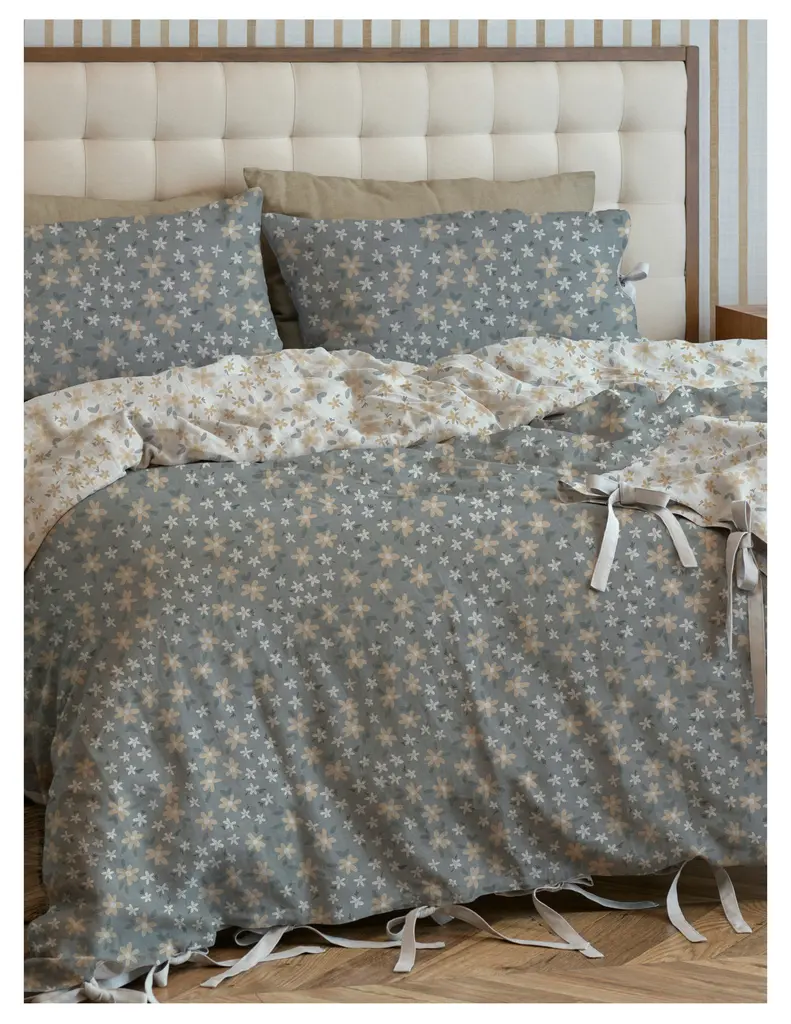 Cozy bed with a light gray star-patterned duvet and matching pillows, complemented by a beige accent pillow, against a tufted headboard.