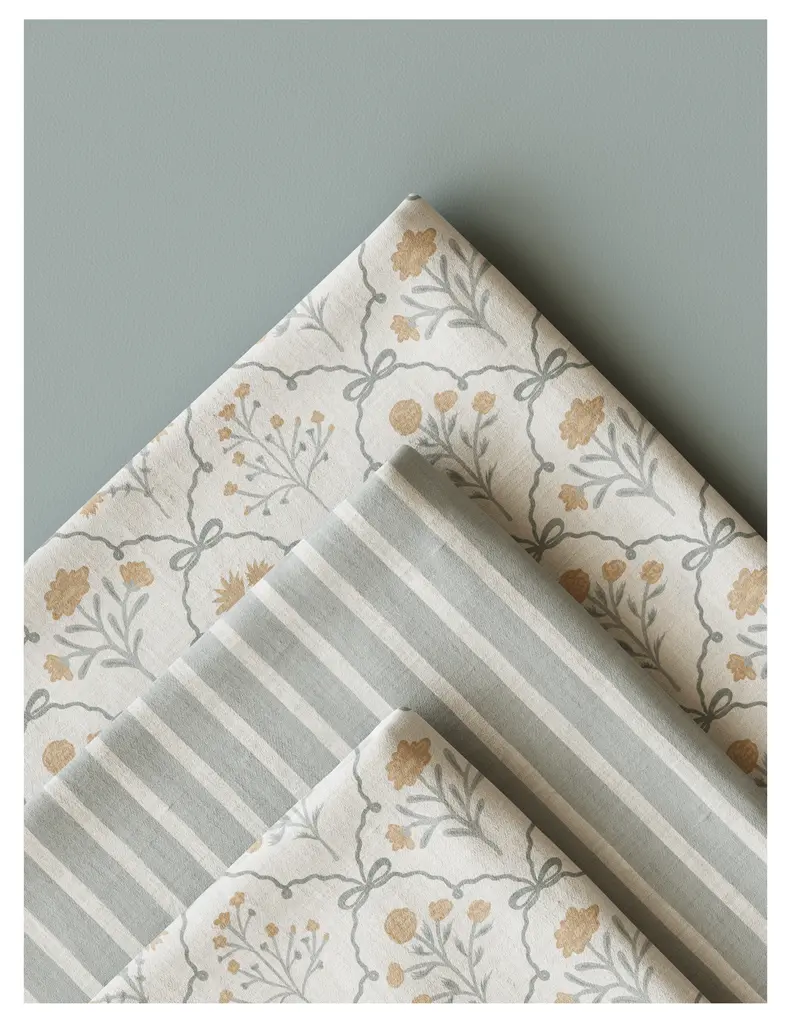 Three patterned fabric pieces arranged neatly, featuring floral designs in soft colors and a striped pattern.