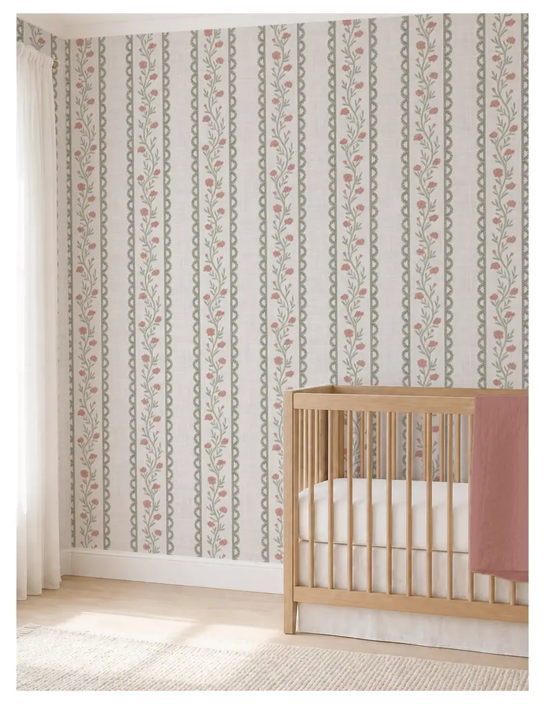 A nursery room featuring a wooden crib against a floral patterned wallpaper with vertical stripes, and soft natural lighting.